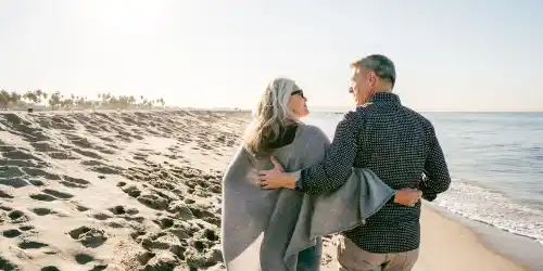 Pareja madura caminando en la playa con seguro de vida vitalicio - Grupo Encino